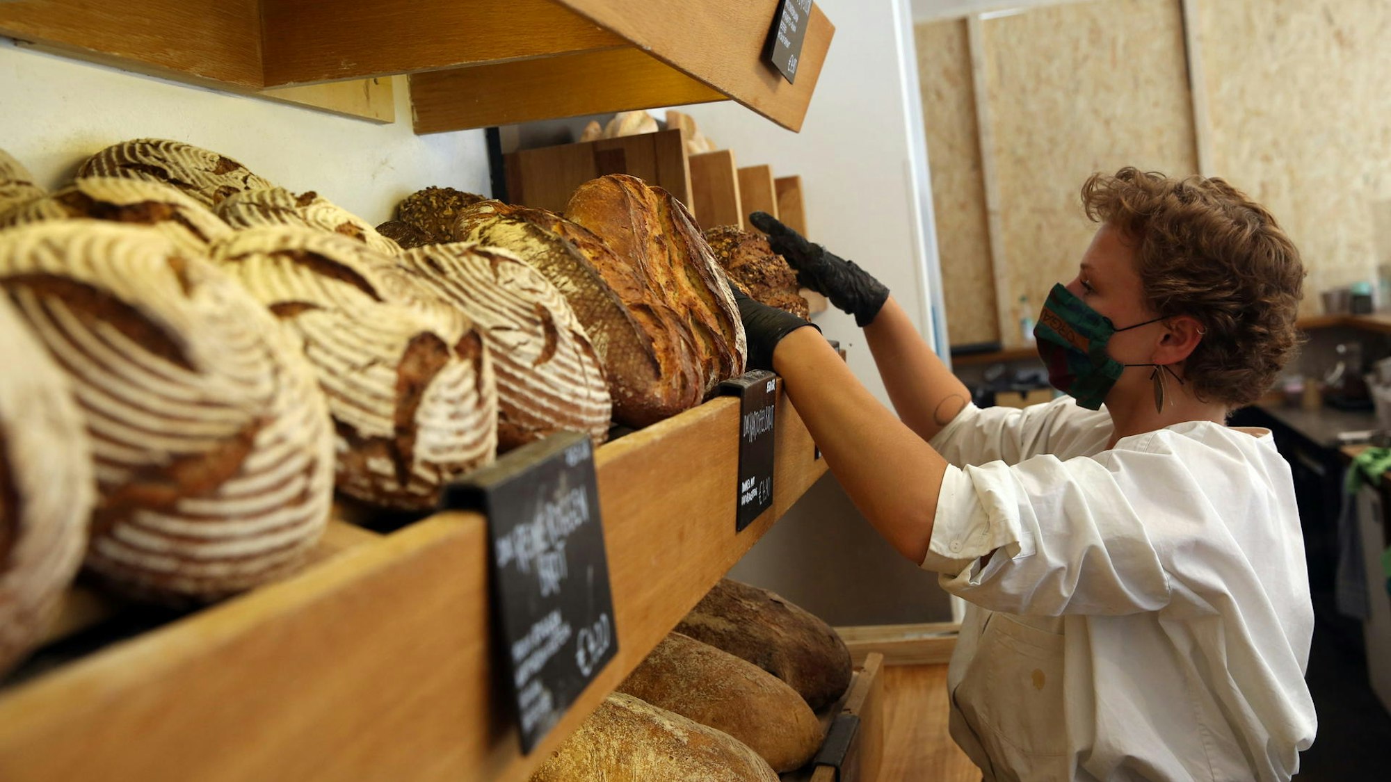 Ein Mensch sortiert frische Brote in einem Regal