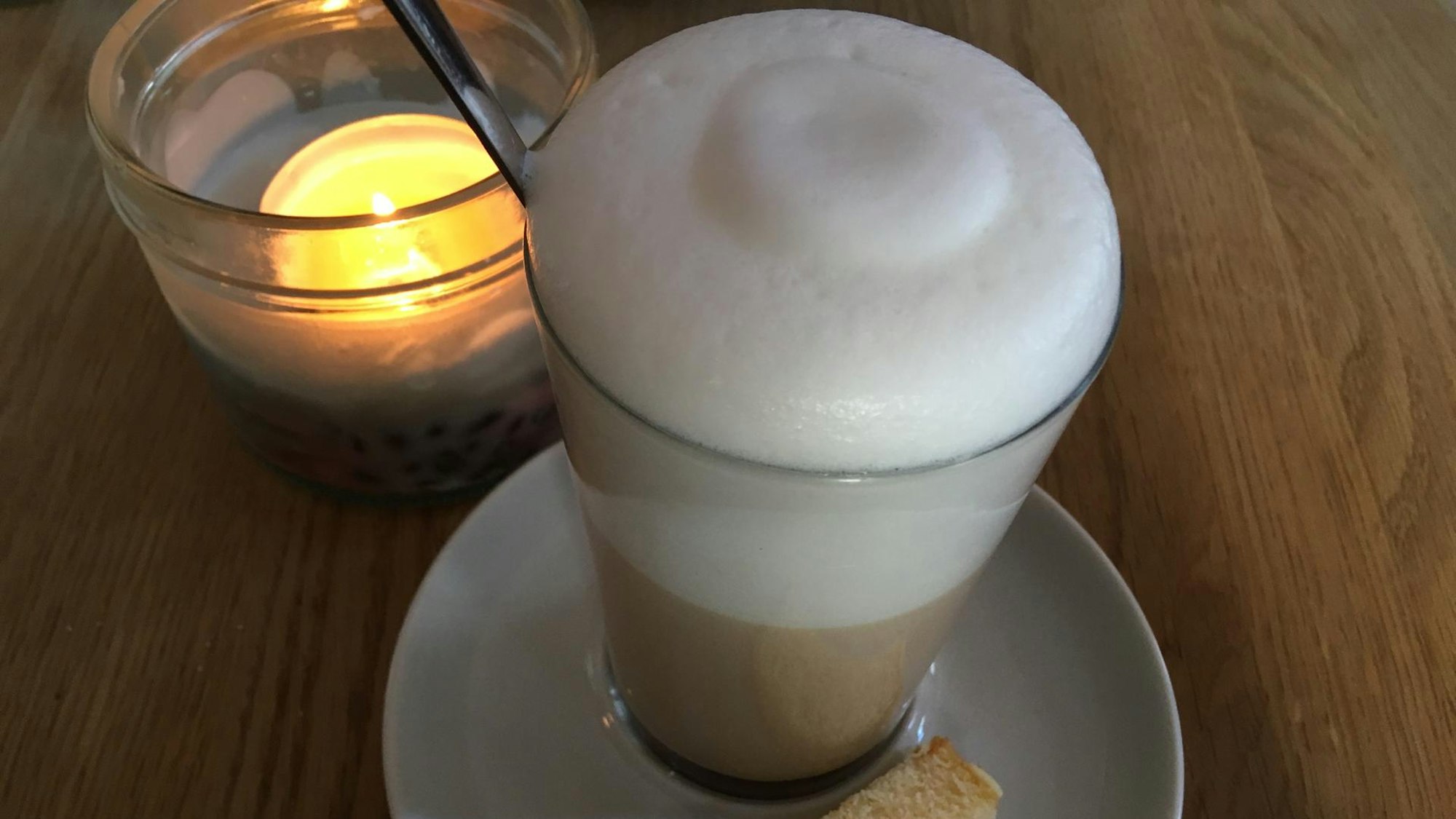 Haptilu Chai Latte steht neben einer Kerze auf einem Tisch im Haptilu