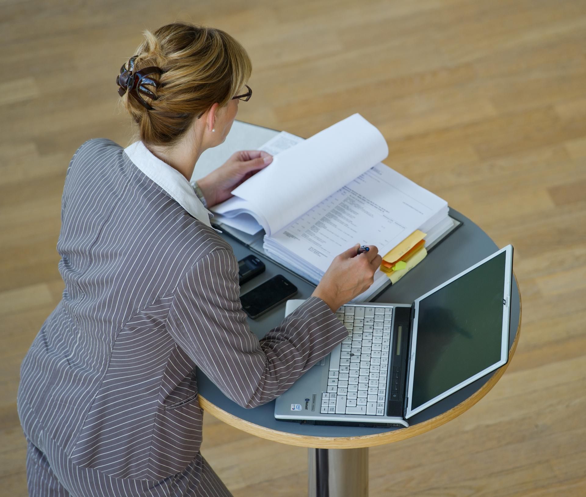 Frau steht an Stehtisch und arbeitet