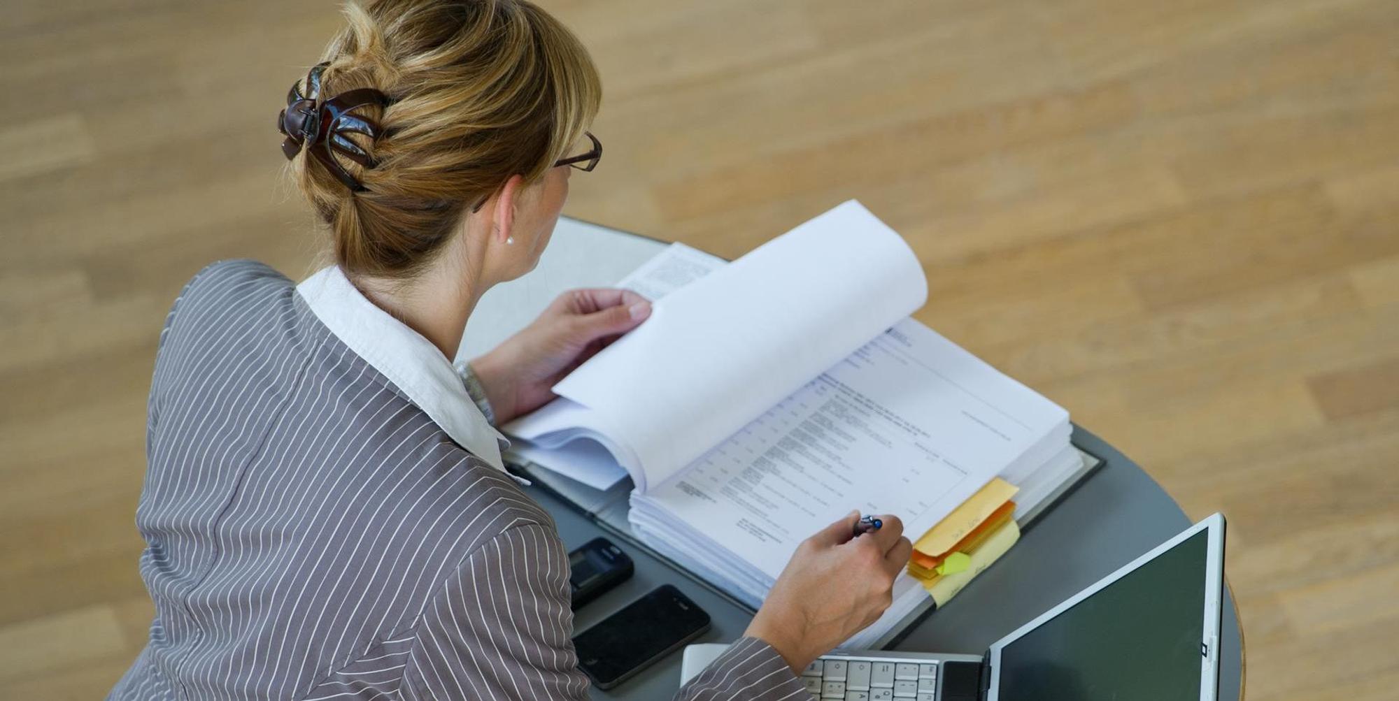 Frau steht an Stehtisch und arbeitet