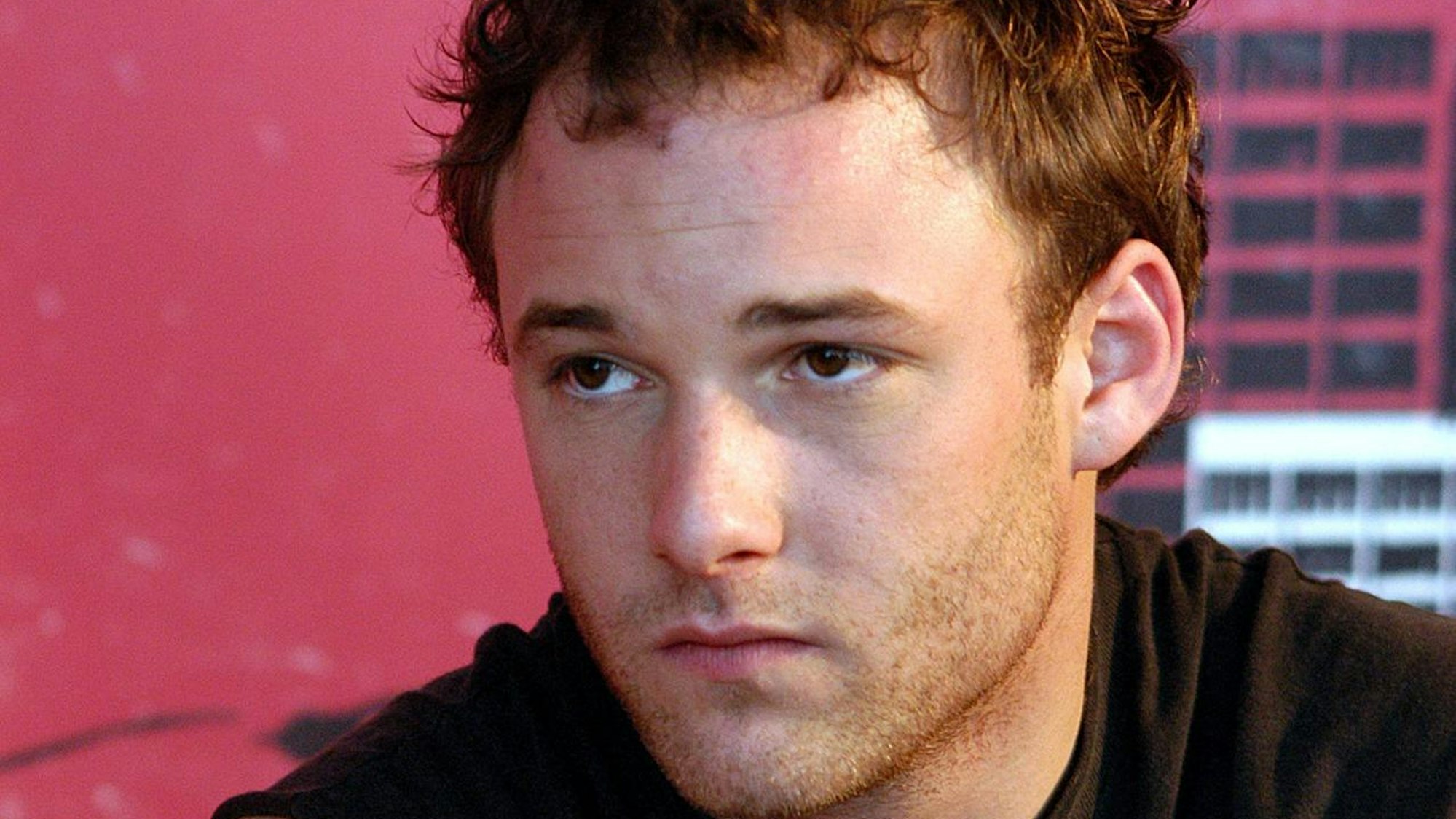 Brad Renfro schaut mit ernster Mine seitlich an der Kamera vorbei. Er trägt ein schwarzes Tanktop und einen Dreitagebart.