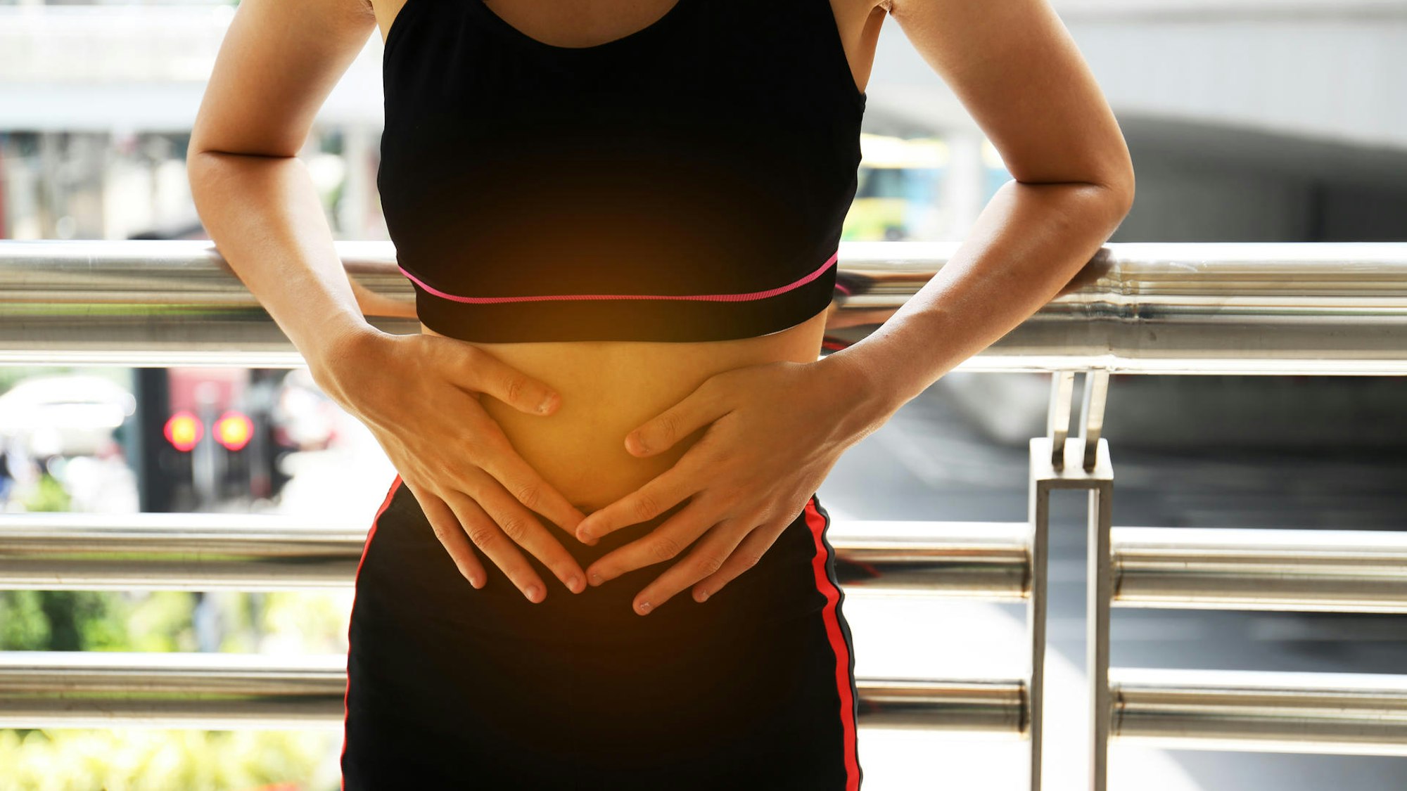 Eine Frau in Sportkleidung hält sich den Bauch.