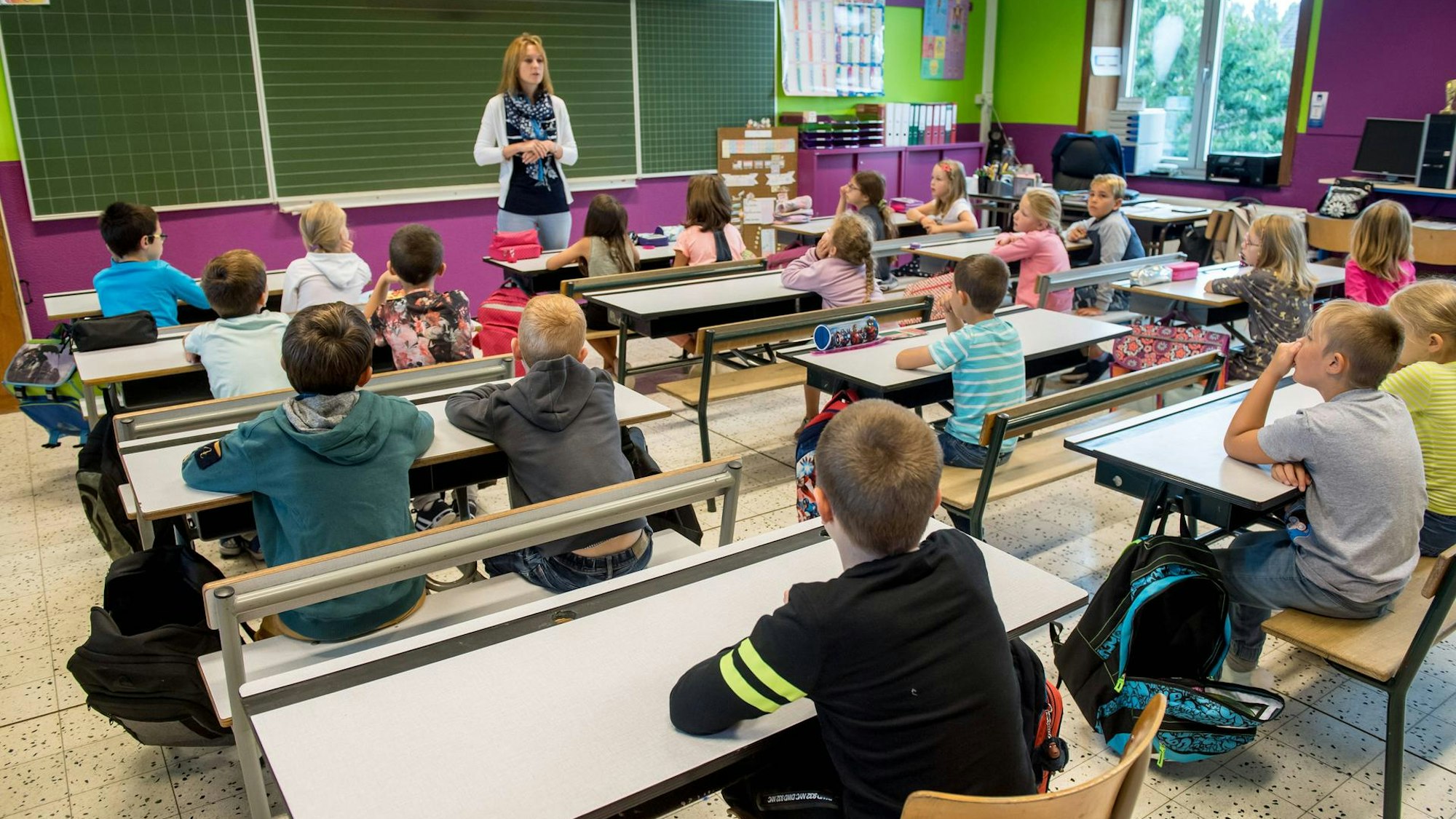 Eine Lehrerin steht vor einer Klasse.