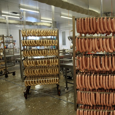 Zwei Wagen, vollgehängt mit Würsten, stehen in einer Verarbeitungshalle der Firma Remagen.