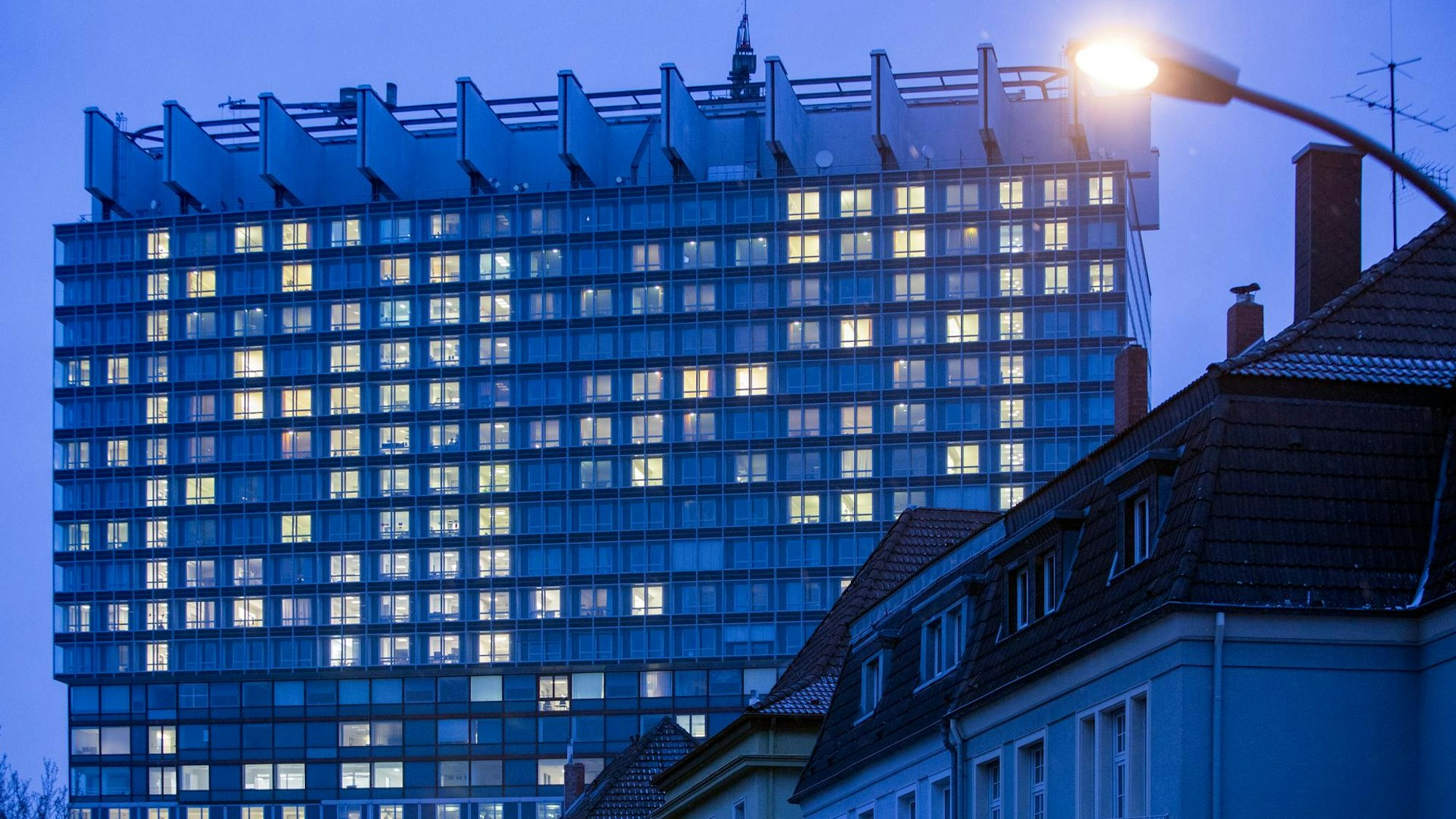 Die Fenster eines Hochhauses der Uniklinik sind in der Dämmerung hell erleuchtet.