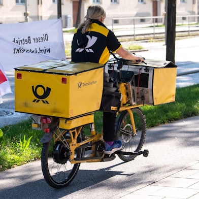 Postbotin mit Verdiflagge