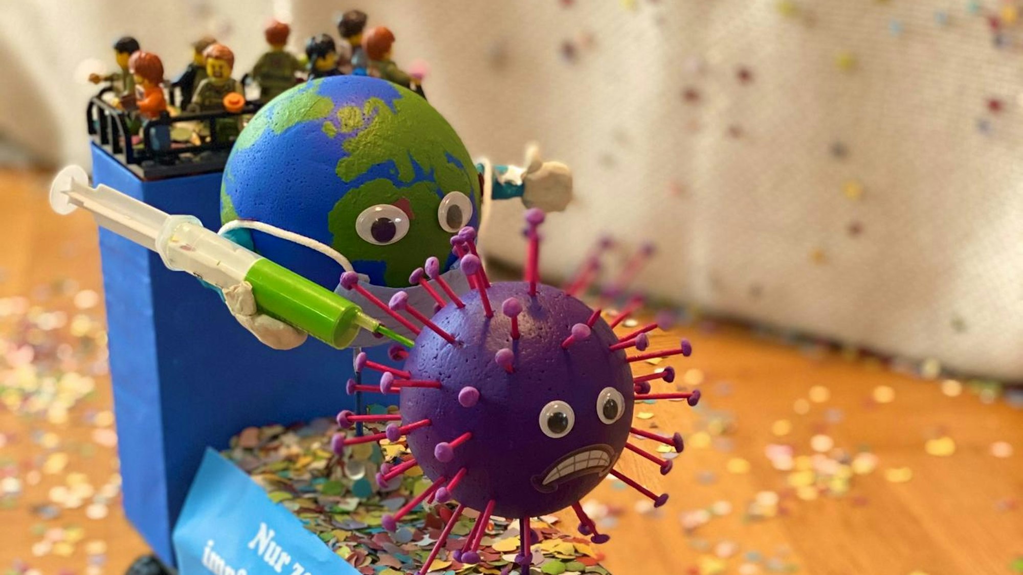 Auf Arthurs Wagen aus Lego ist eine Weltkugel mit Maske zu sehen, die dem Coronavirus eine Impfspritze verpasst.