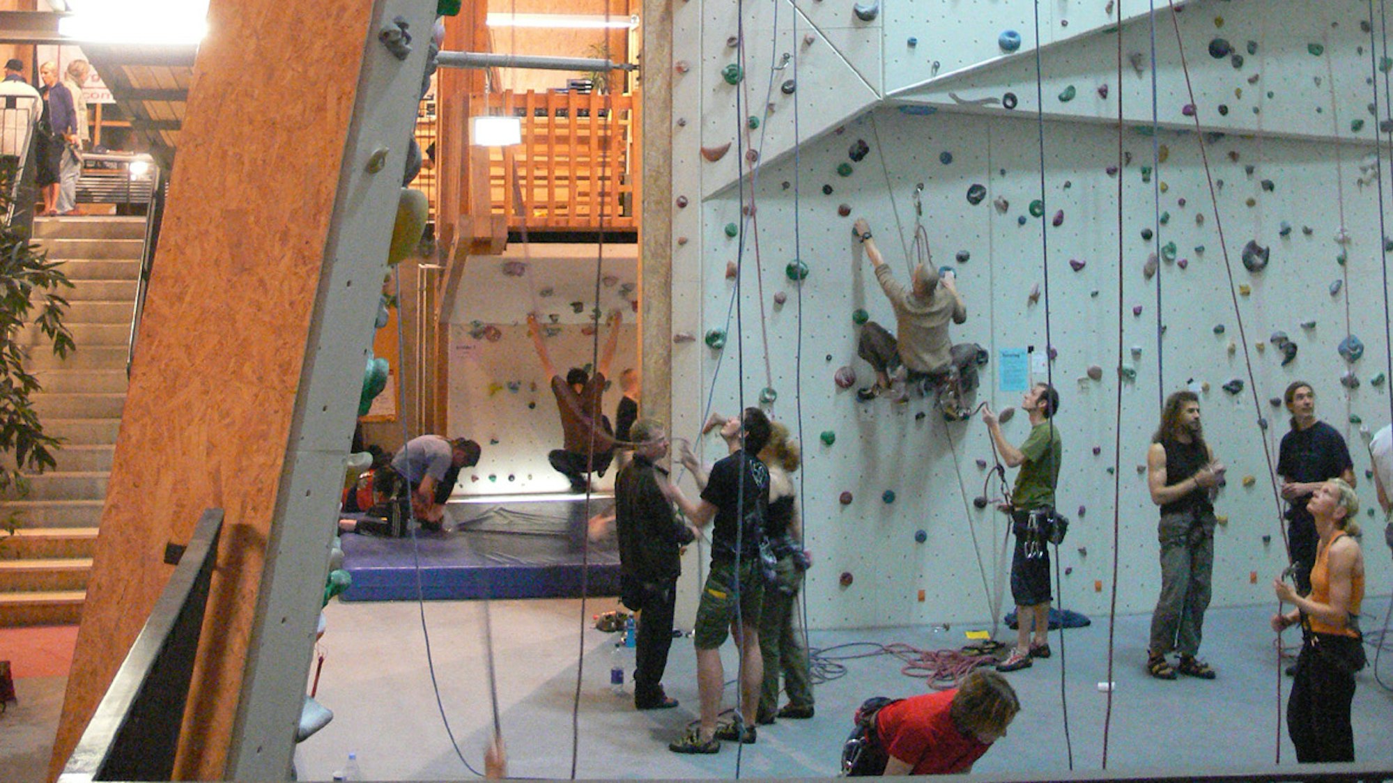 Viele Menschen stehen an einer Kletterwand.