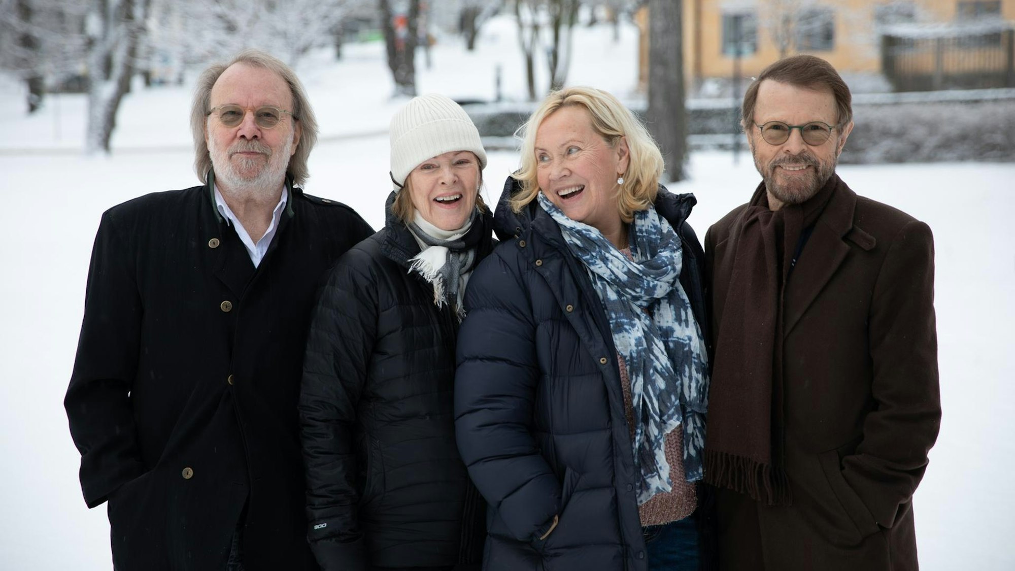Benny, Frida, Agnetha und Björn posieren lachend im Schnee.