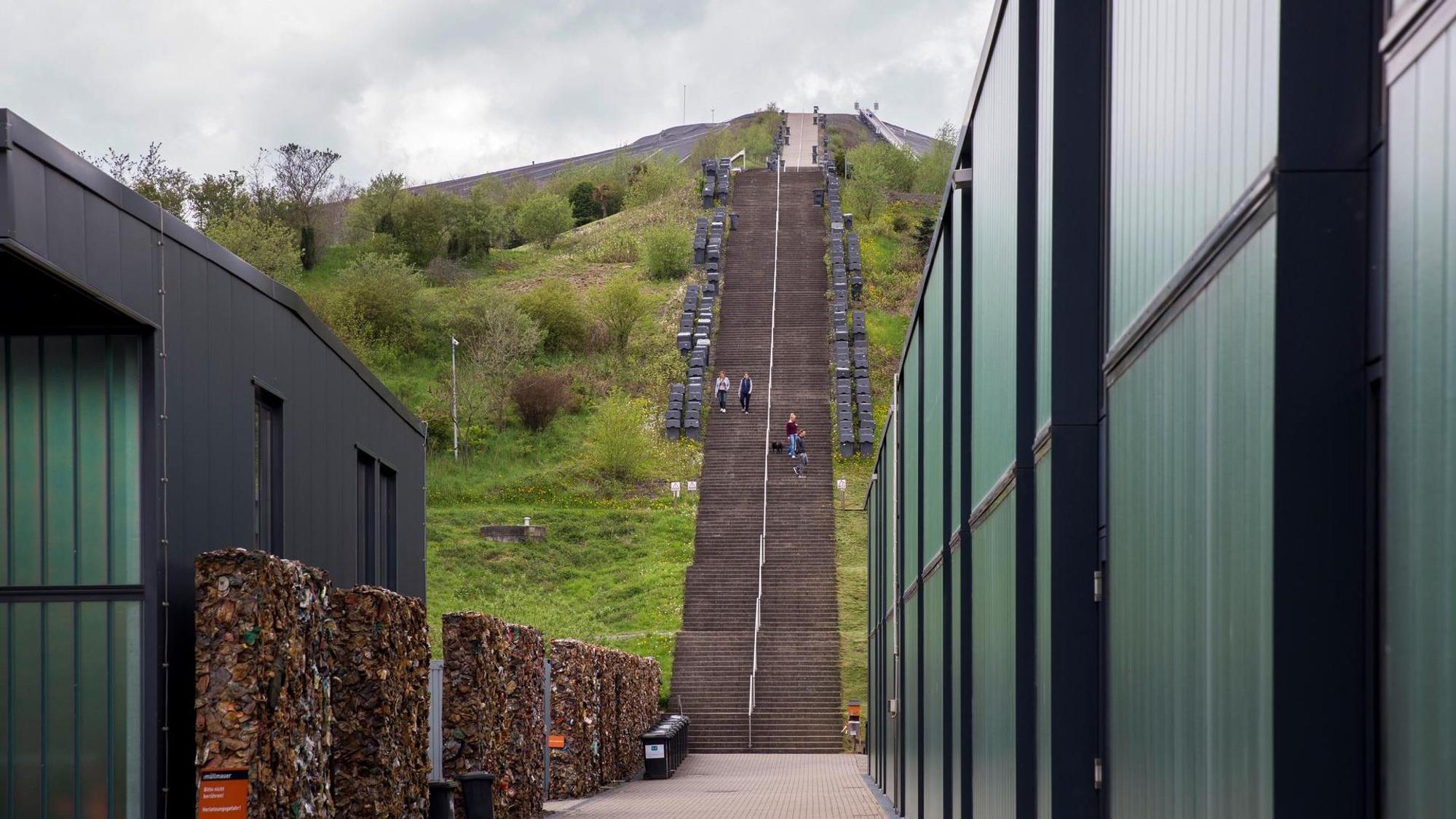 Blick zwischen zwei Gebäuden hindurch auf eine lange Treppe, die einen Berg hinaufführt