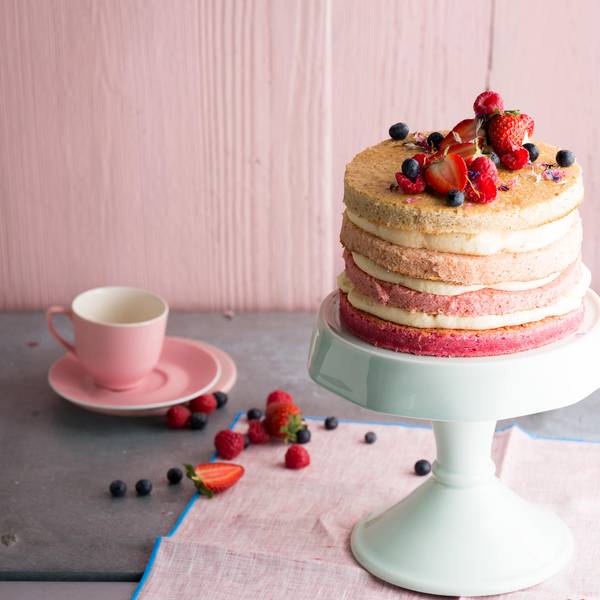 Eine schöne, zartrosa Torte mit leckeren Schichten wird auf einem Tortenteller präsentiert.