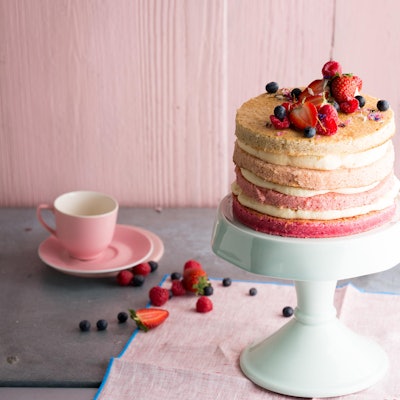 Eine schöne, zartrosa Torte mit leckeren Schichten wird auf einem Tortenteller präsentiert.