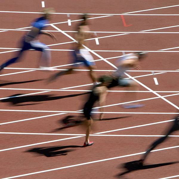 Mehrere Menschen rennen und verschwimmen dabei auf einem typisch roten Feld.