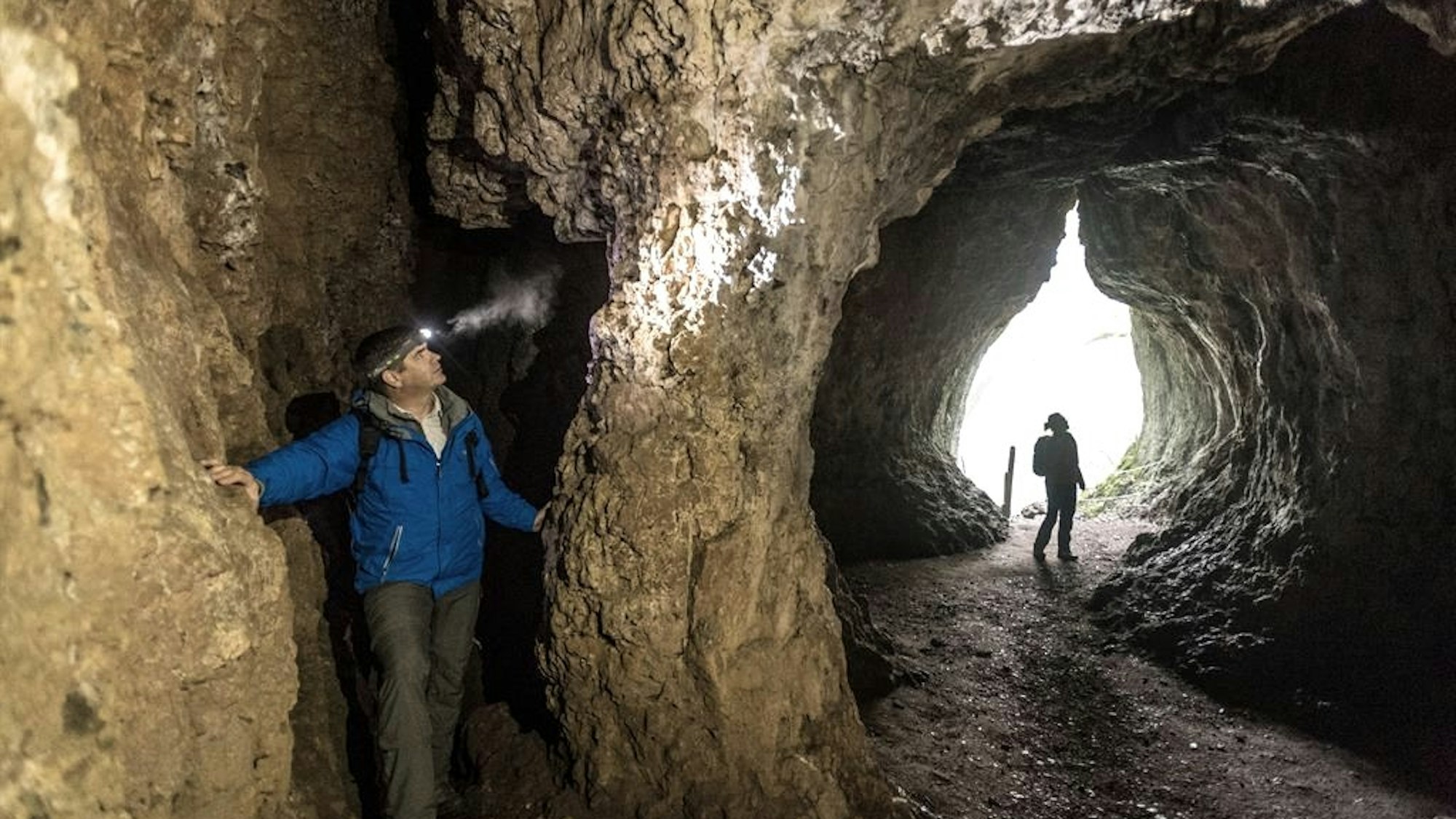 zwei Besucher erkunden eine Höhle
