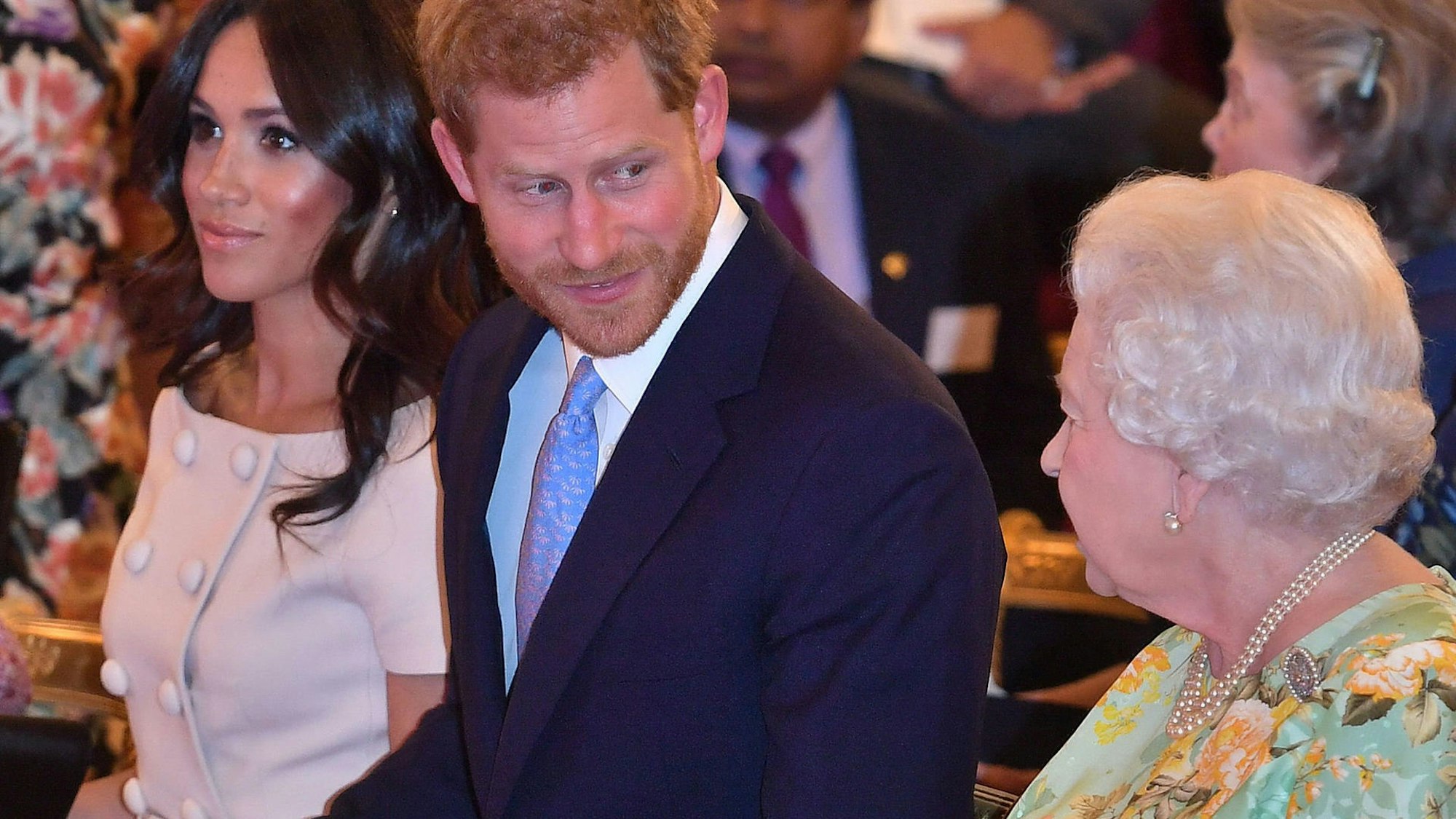 Prinz Harry blickt lächelnd zu Queen Elizabeth II., während Meghan, Herzogin von Sussex, an seiner Seite sitzt.