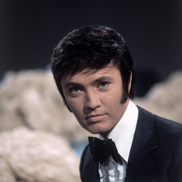 Schlagerstar Rex Gildo bei einem Auftritt in einer Fernsehshow um 1969. Er schaut neutral in die Kamera.