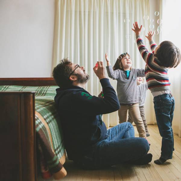 Ein Vater macht mit seinen Kindern Seifenblasen.