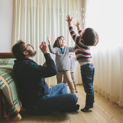 Ein Vater macht mit seinen Kindern Seifenblasen.