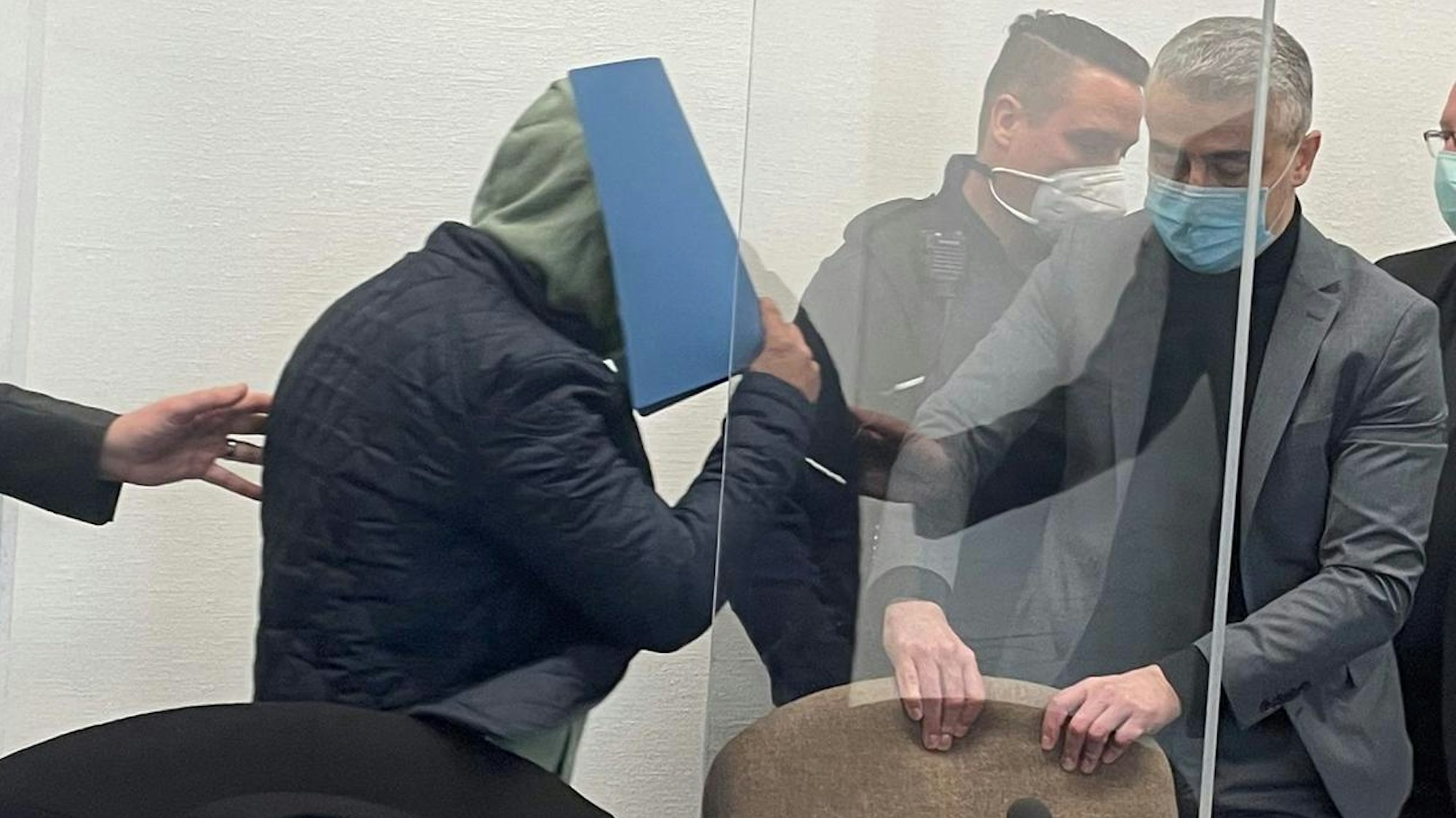 Der Angeklagte mit Verteidiger Mustafa Kaplan und einem Wachtmeister im Landgericht Köln.