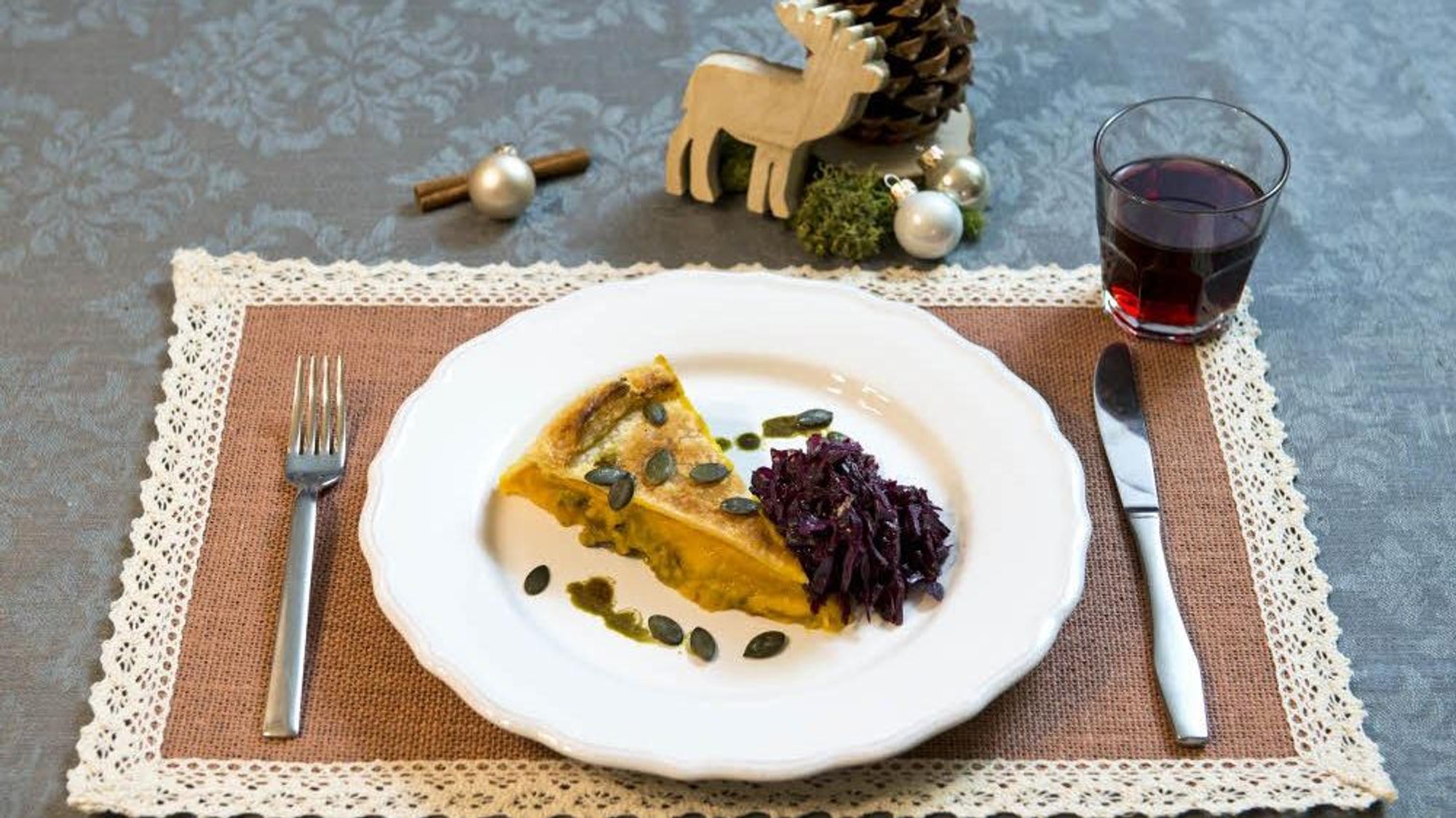 Ein Stück Kürbispastete liegt mit einer Portion Rotkohl lecker angerichtet auf einem Teller.