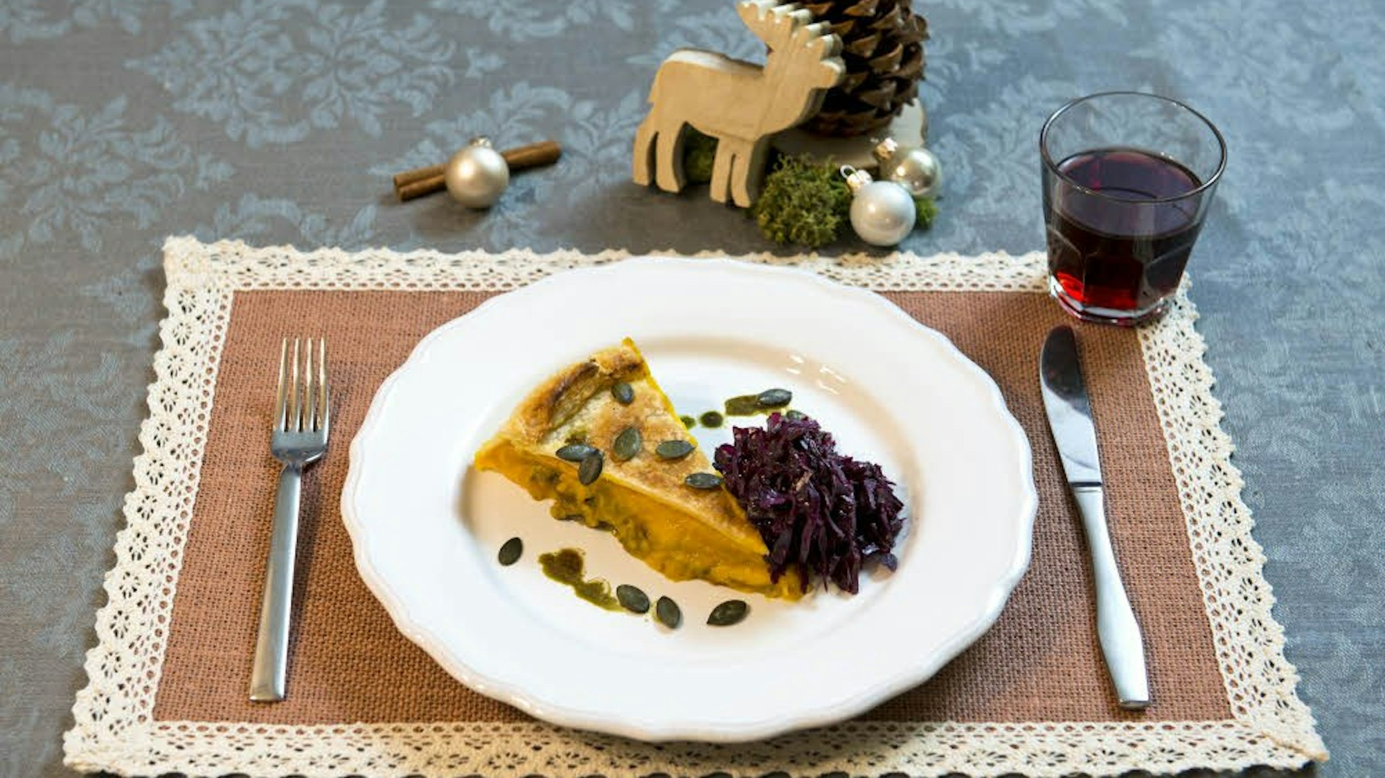 Ein Stück Kürbispastete liegt mit einer Portion Rotkohl lecker angerichtet auf einem Teller.