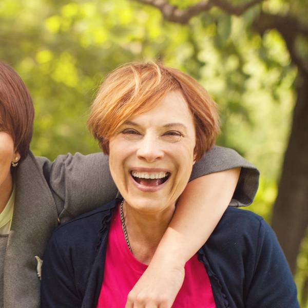 Zwei Frauen mittleren Alters lachen miteinander.