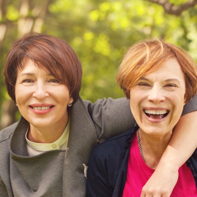 Zwei Frauen mittleren Alters lachen miteinander.