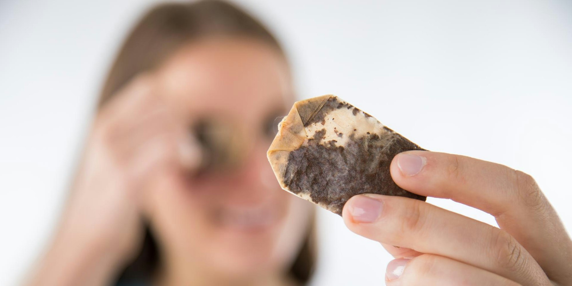 Frau legt sich Teebeutel auf die Augen