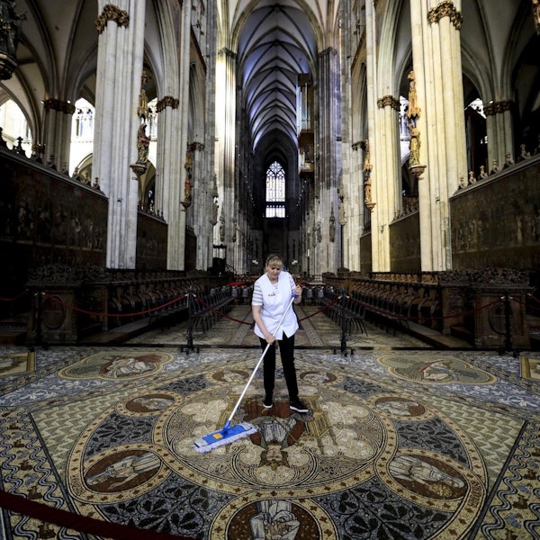 Eine Reinigungskraft wischt das Mosaik zwischen Chorgestühl und Dreikönigenschrein.
