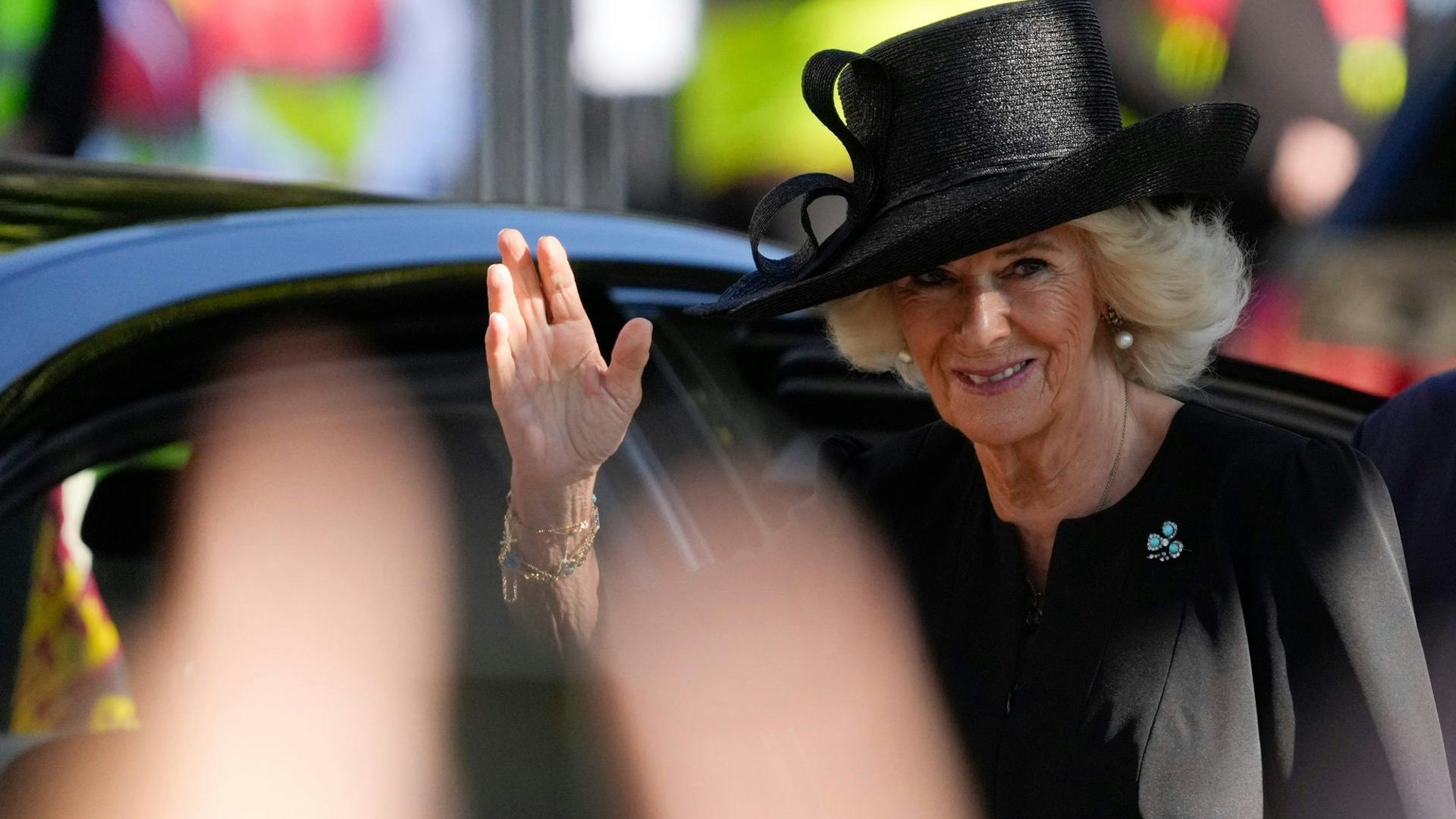 Königin Camilla winkt den Menschen zu.