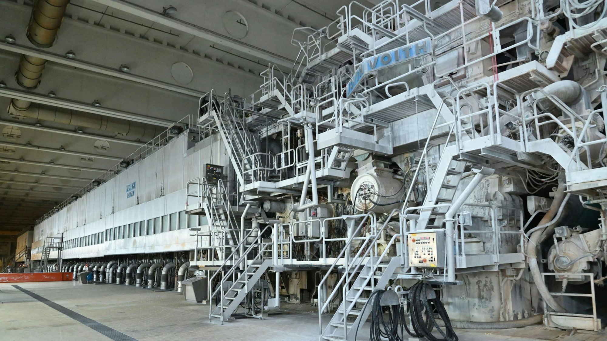 Eine riesige Papiermaschine in einer Halle.