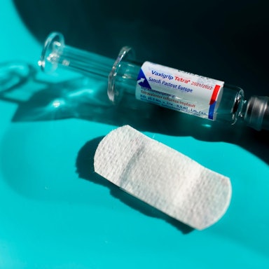 Eine Spritze und ein Pflaster liegen auf einem Tisch bereit.