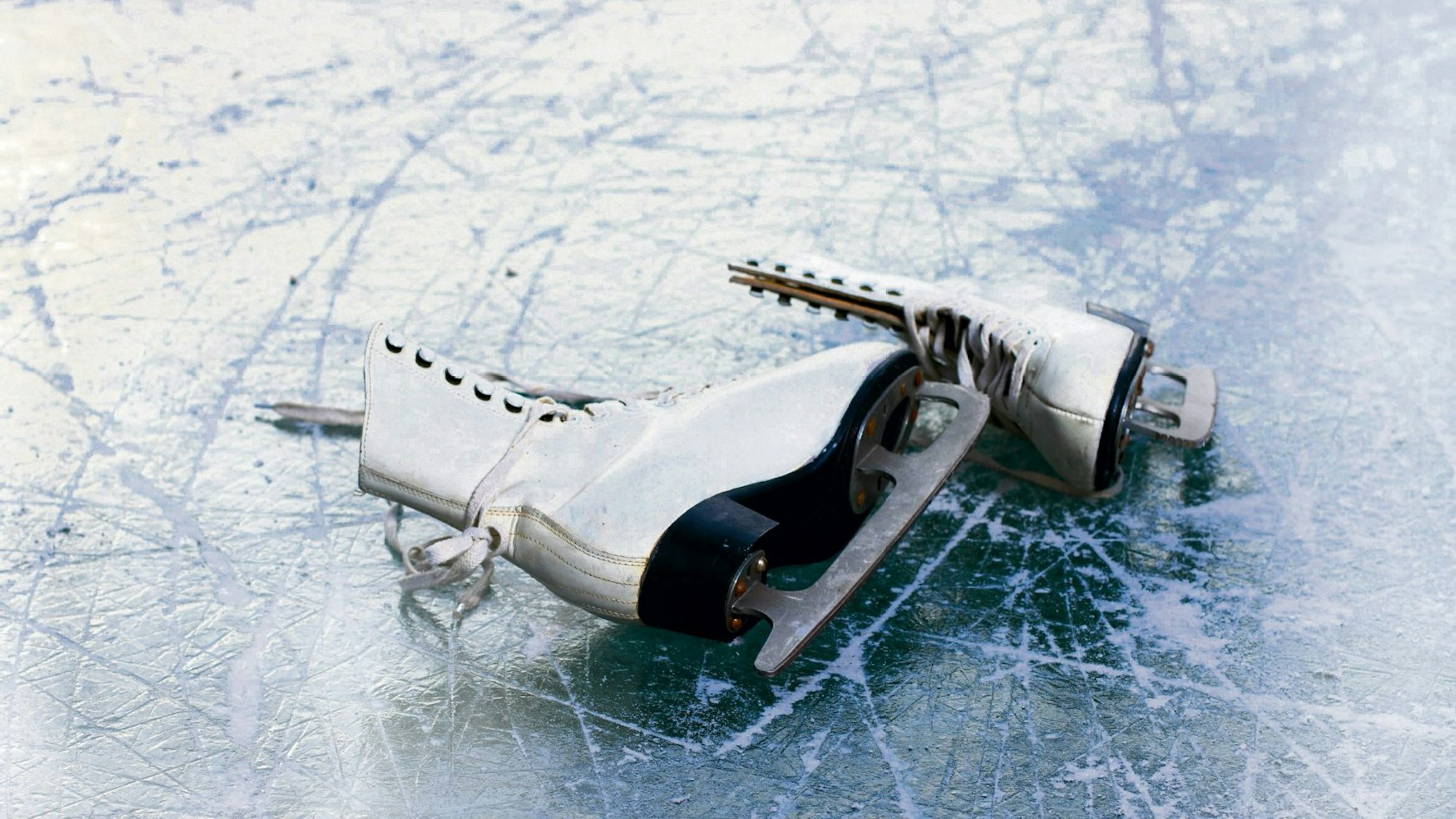 zwei weiße Schlittschuhe liegen auf dem Eis