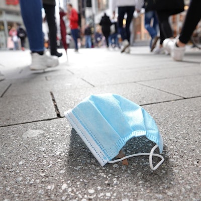 Eine Maske liegt in einer Fußgängertrasse auf dem Boden.