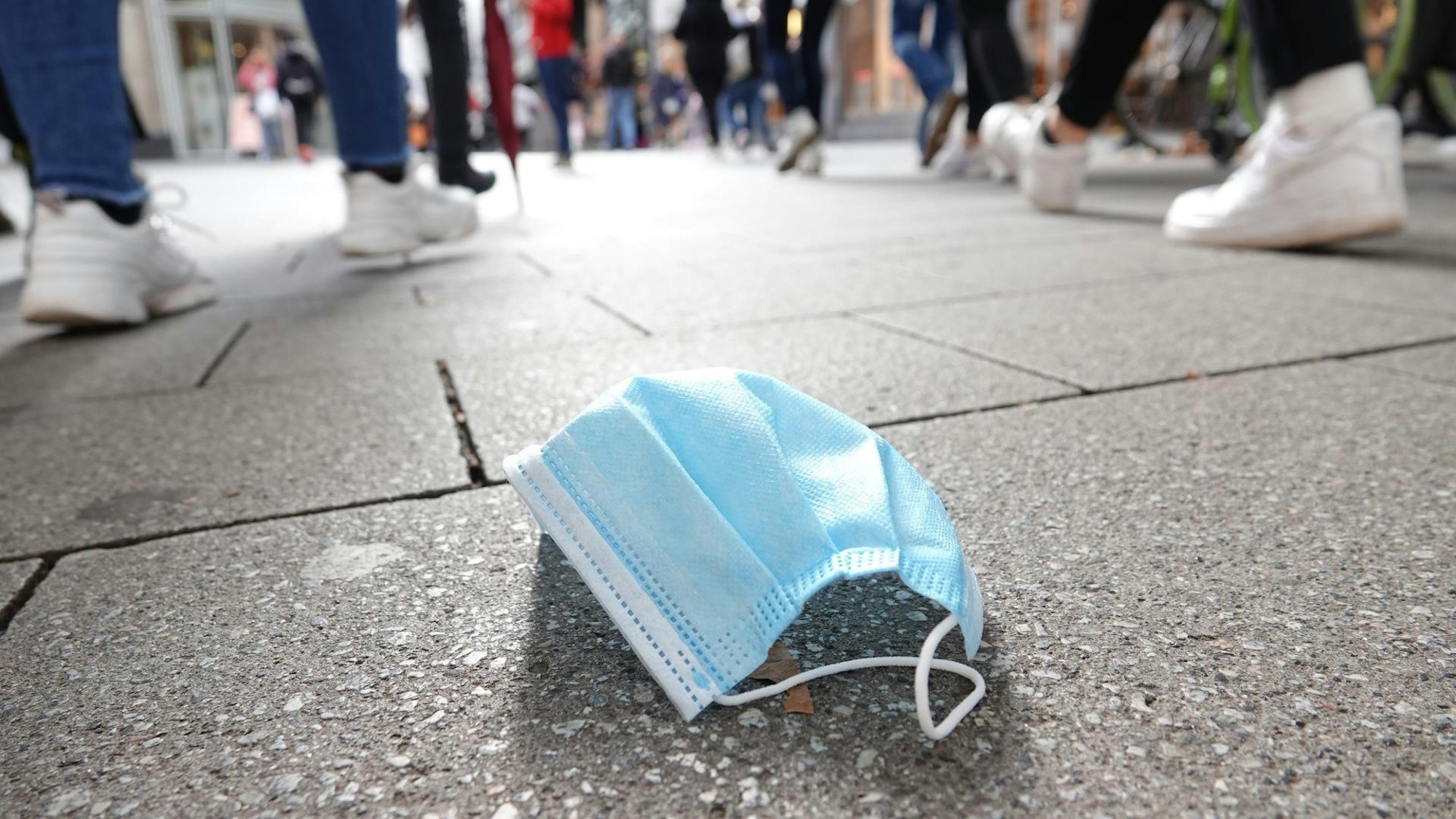 Eine Maske liegt in einer Fußgängertrasse auf dem Boden.