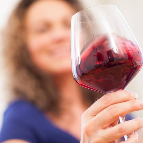 Frau hält ein Gas Rotwein in der Hand