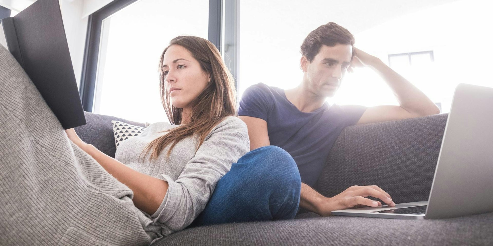 Mann_und_Frau_sitzen_mit_eigenem_Laptop_auf_dem_Sofa