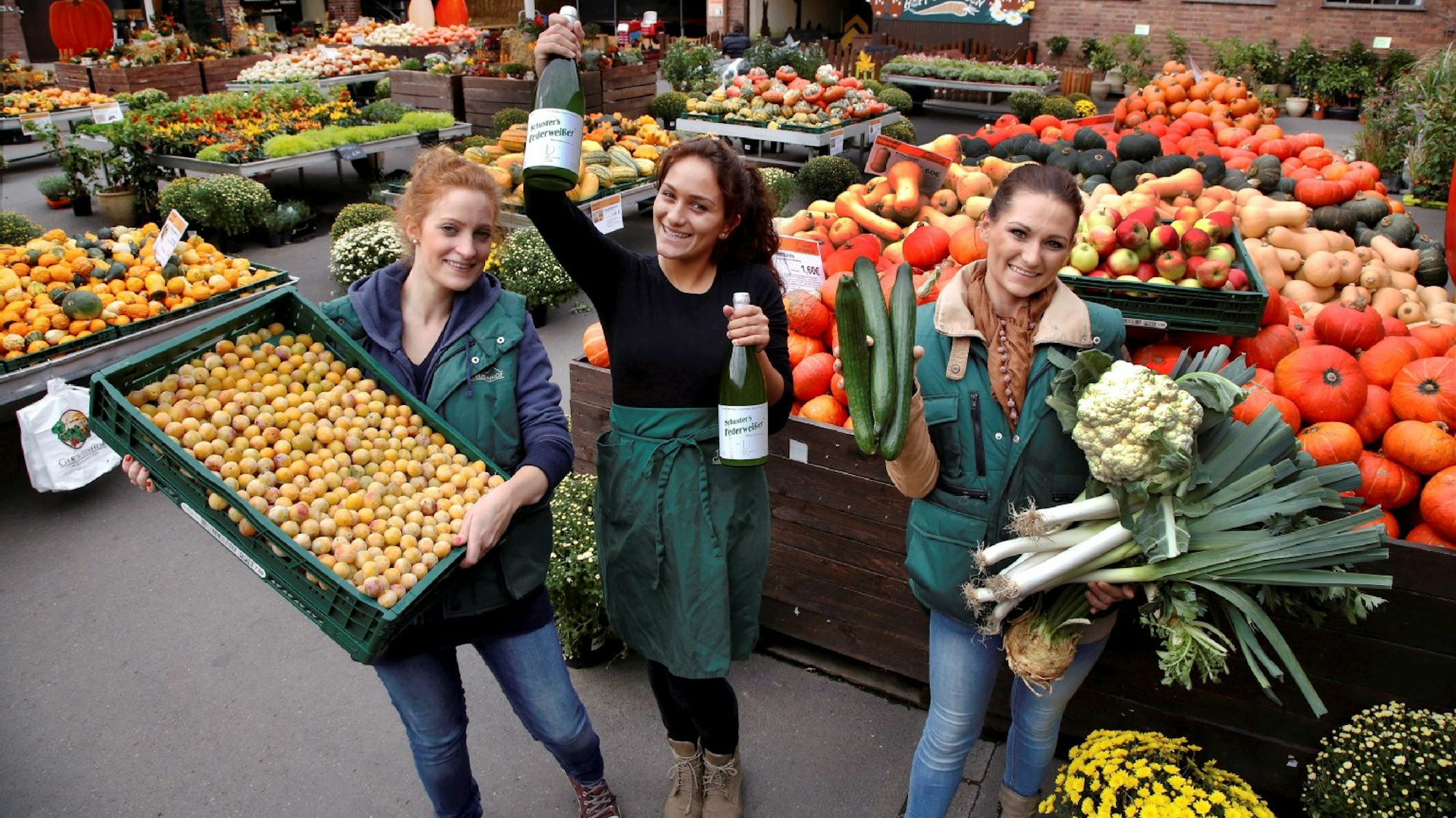 Die Mitarbeiterinnen des Hofes zwischen einer riesengroßen Auswahl an Obst und Gemüse