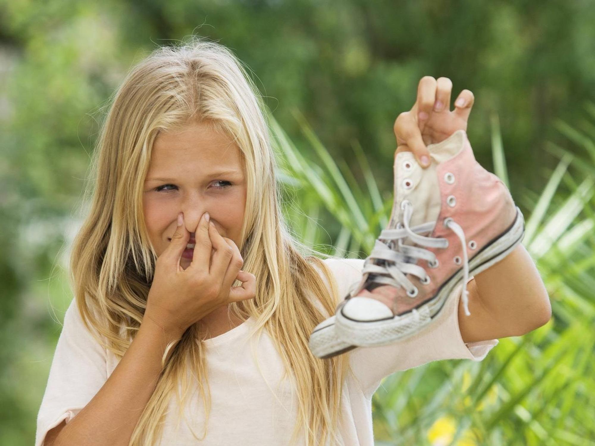 Frau hält stinkende Schuhe in die Luft