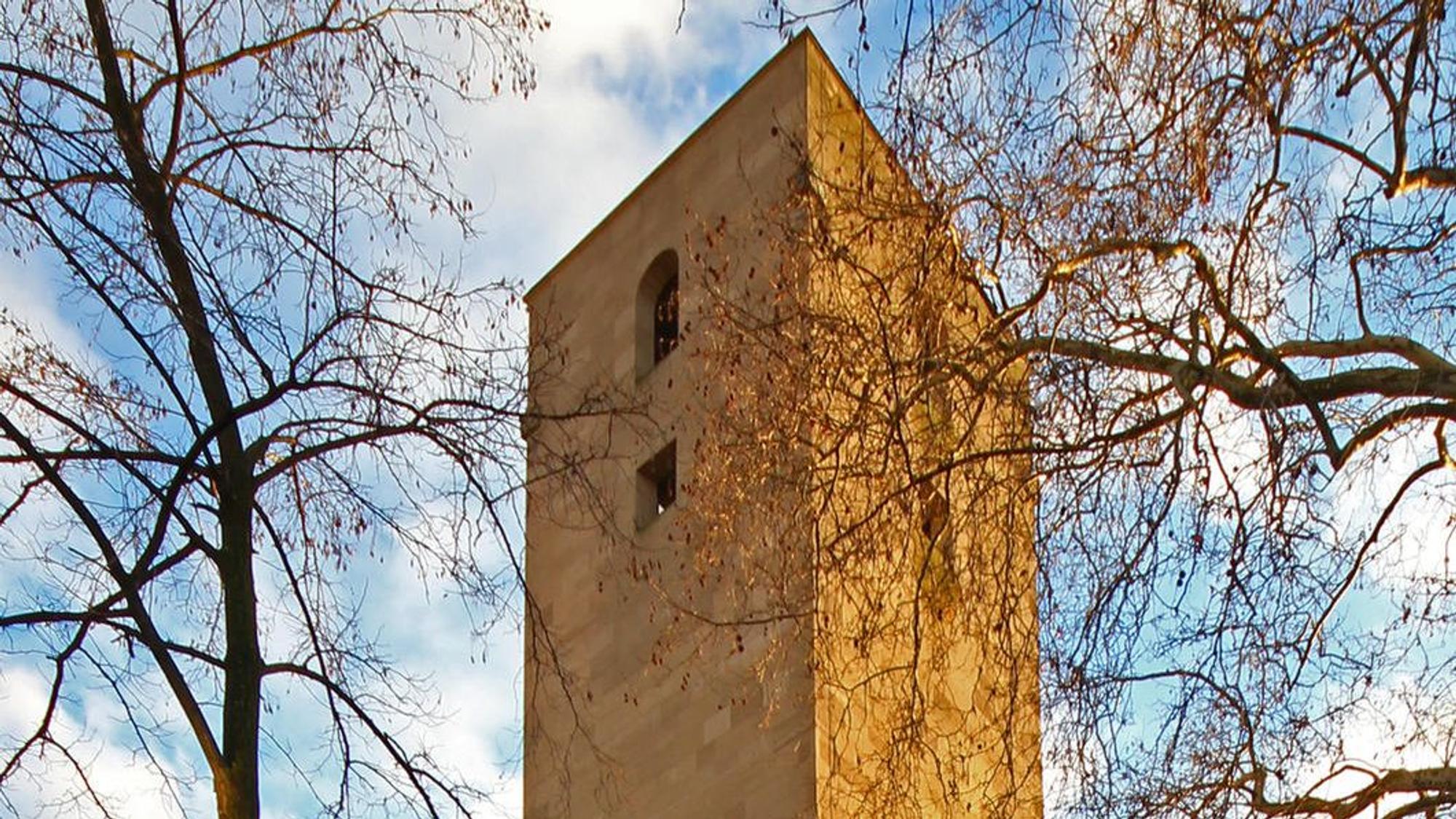 oberer Teil eines Kirchturms zwischen Bäumen