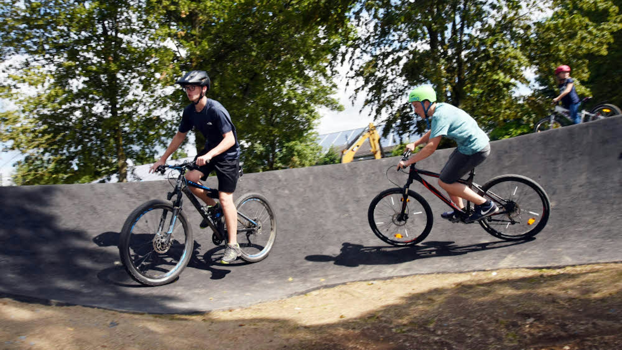 Zwei Jungs fahren mit dem Fahrrad auf einem Pumptrack.
