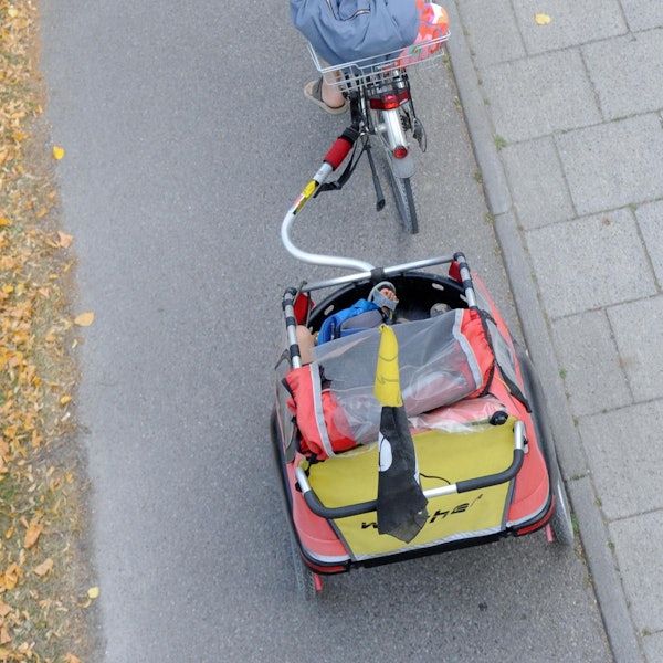 Frau fährt Fahrrad mit Kinderanhänger