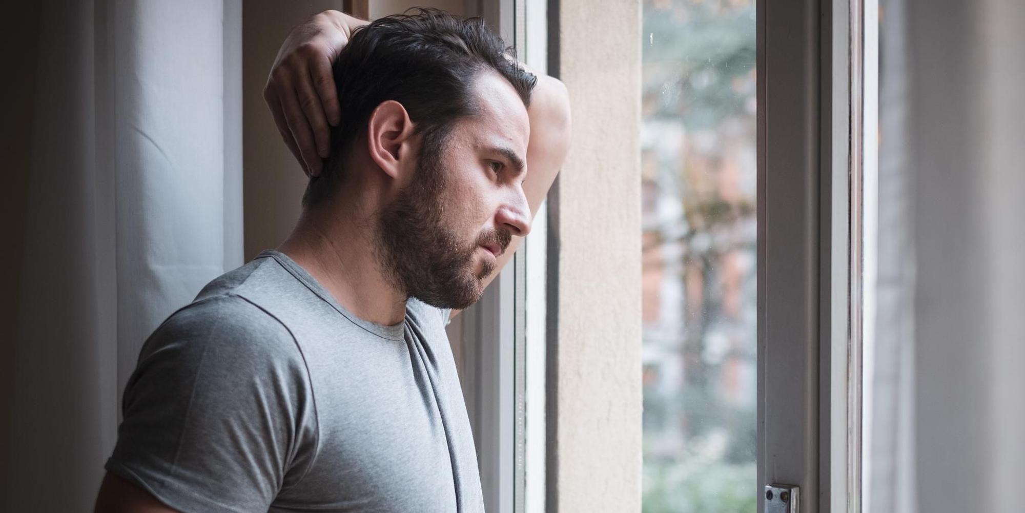 Mann steht an einem Fenster