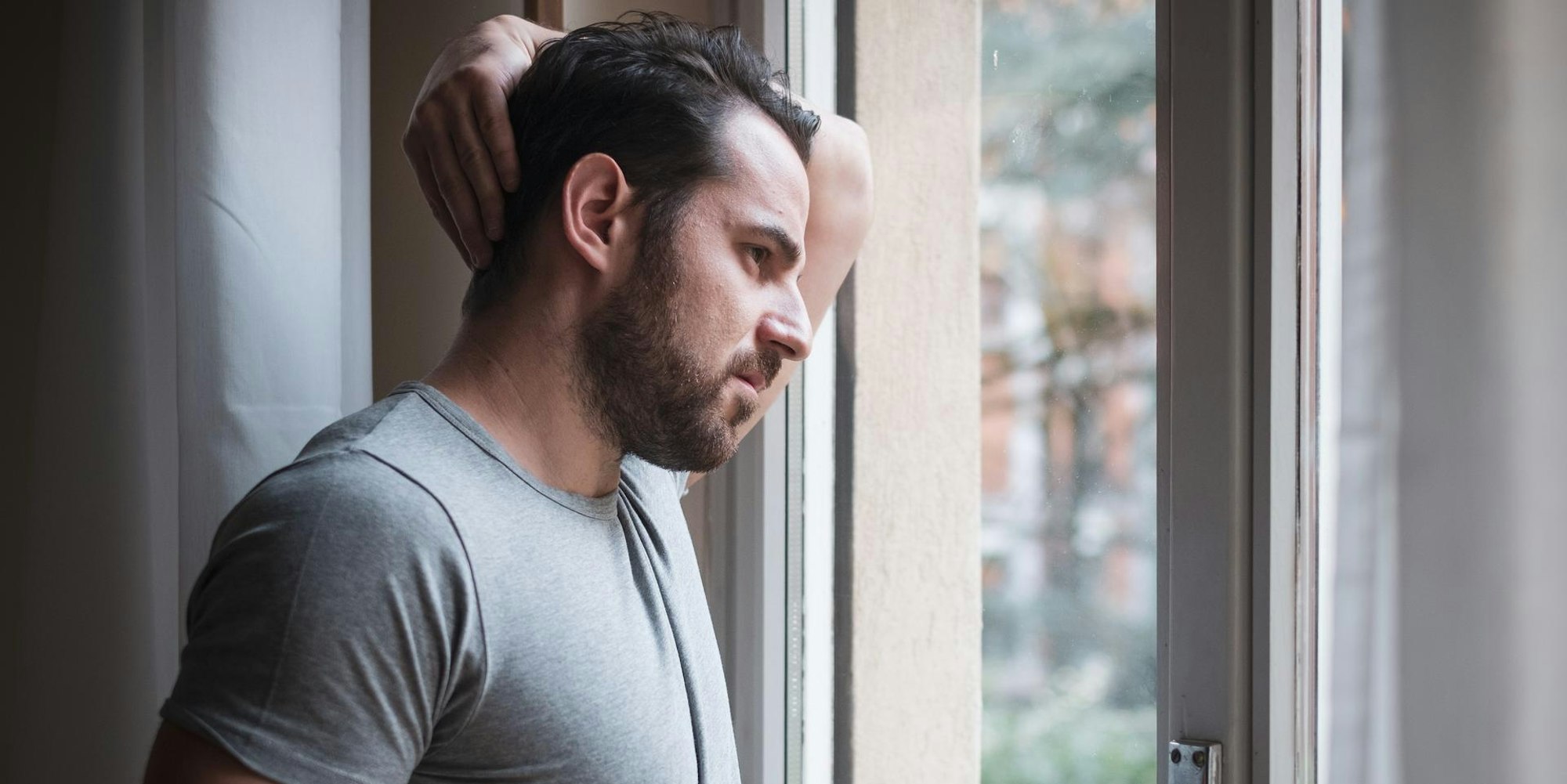 Mann steht an einem Fenster