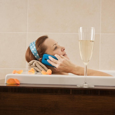 Frau mit Handy in der Wadewanne