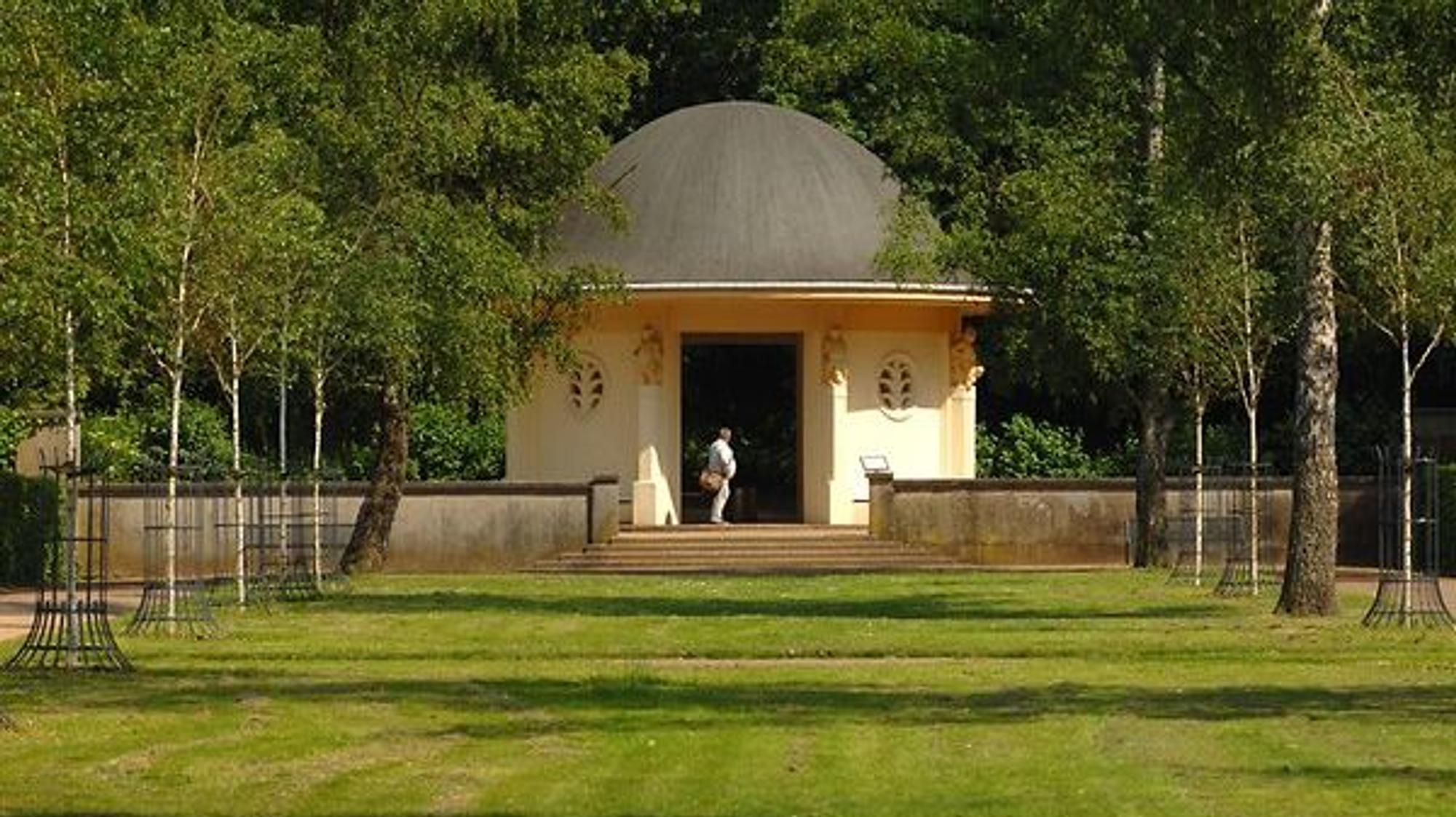 kleines, gelbes Gebäude mit rundem Dach in einem Park