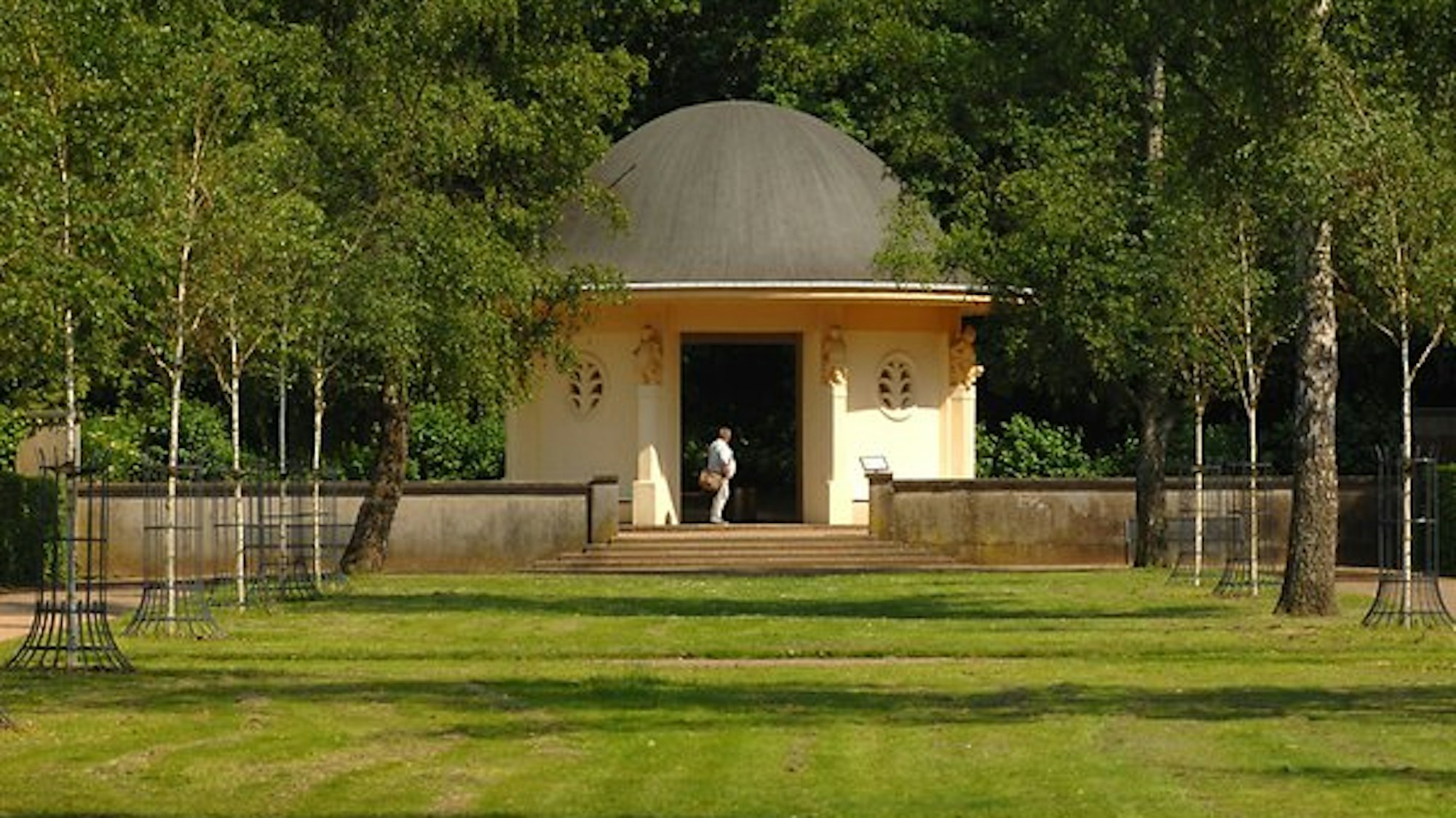 kleines, gelbes Gebäude mit rundem Dach in einem Park
