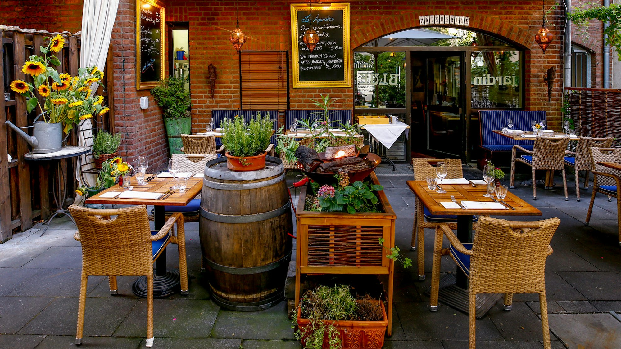 Ein Innenhof mit Holztischen, schön dekoriert mit Pflanzen und Sonnenblumen