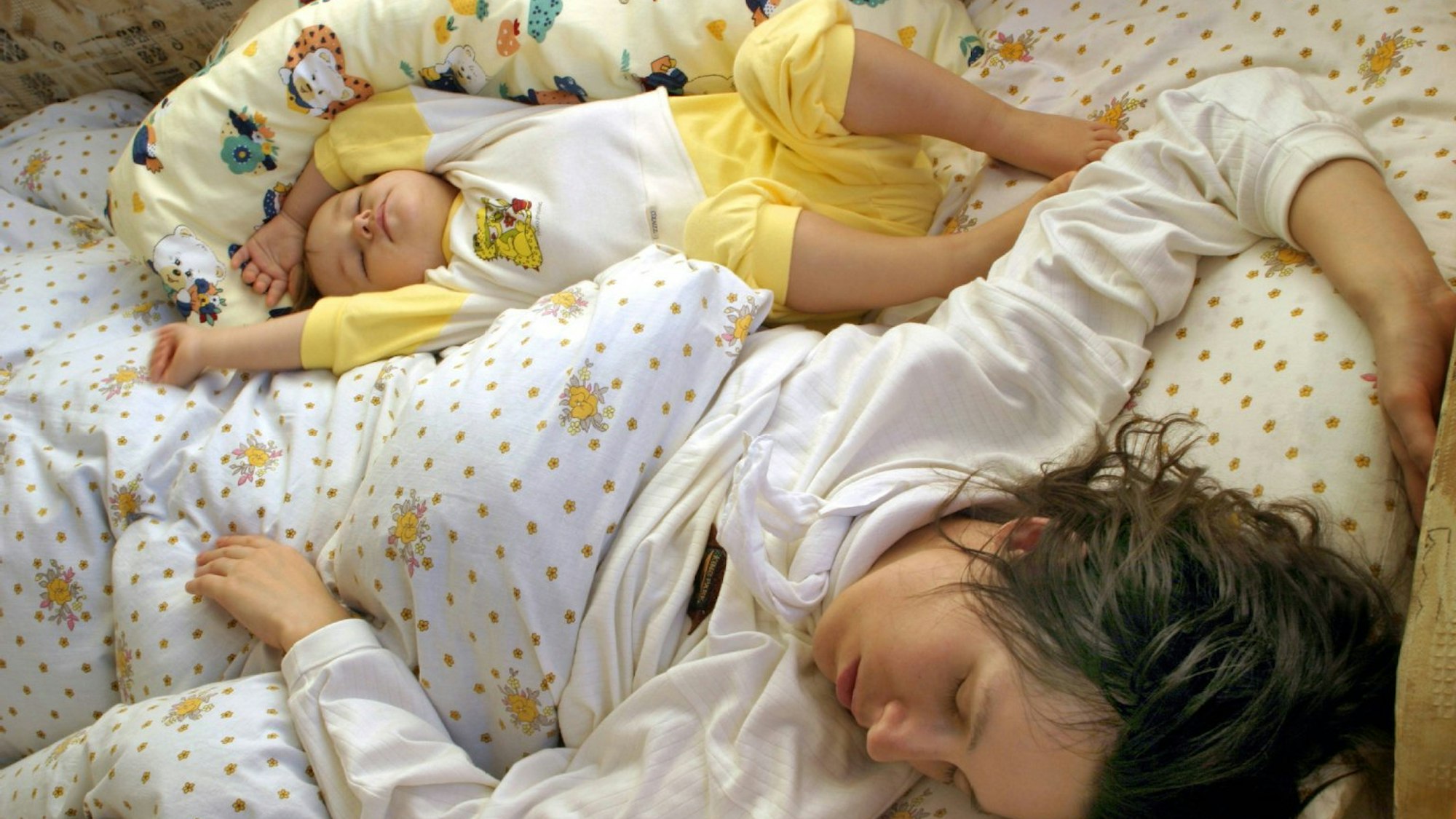 Mutter und Kind schlafen in einem Bett.