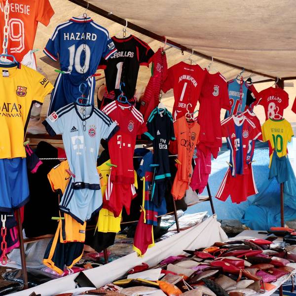 Gefälschte Fußballtrikots hängen an einem Marktstand.